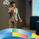 Nate Hoffman, UCLA Communication class of 2024, speaks into a microphone beside a presentation screen in a CCCP 25th anniversary–branded alumni graphic.