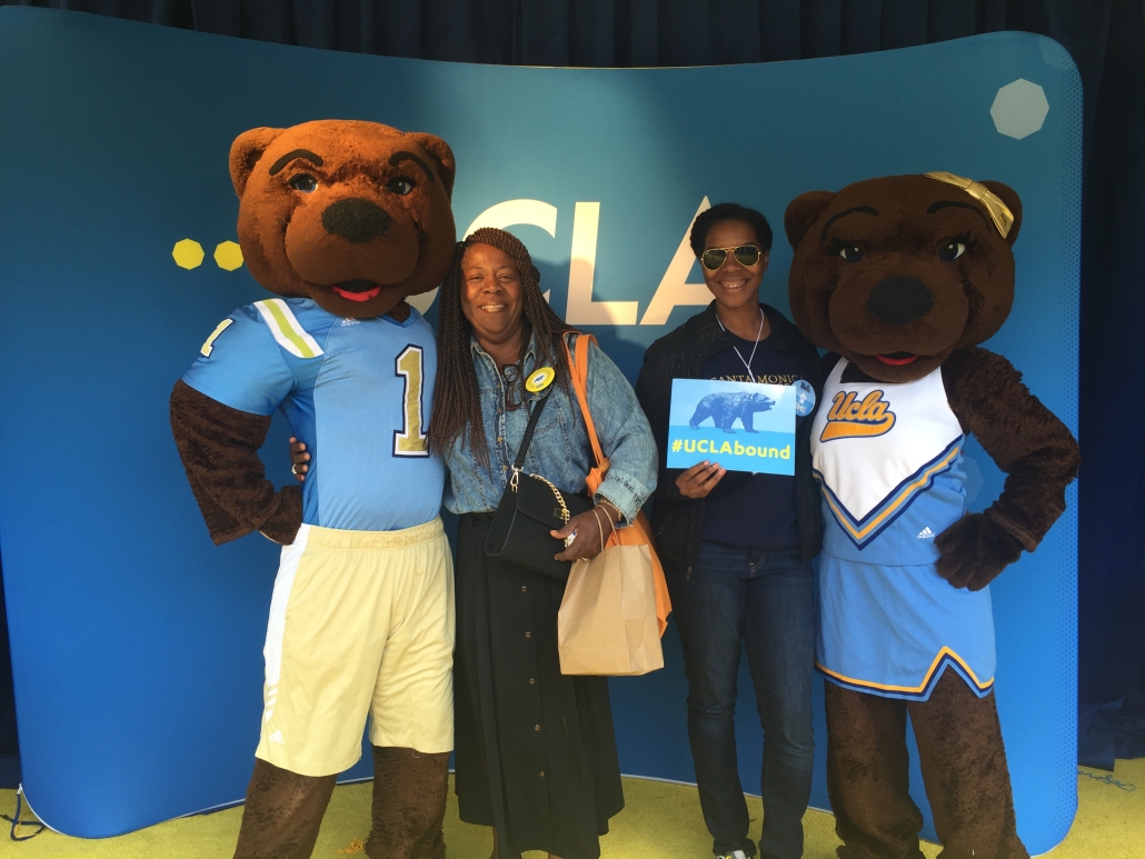 Aurelia and her mother pose between UCLA’s Joe and Josephine Bruin mascots while Aurelia holds a “#UCLAbound” sign.