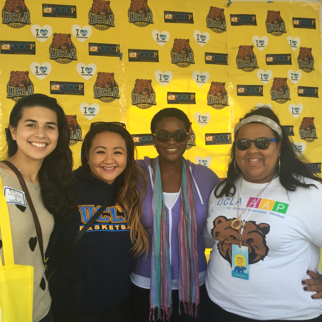 Four women smile together in front of a bright yellow UCLA and CCCP photo backdrop featuring Bruin logos and “I Love UCLA Transfers” graphics.