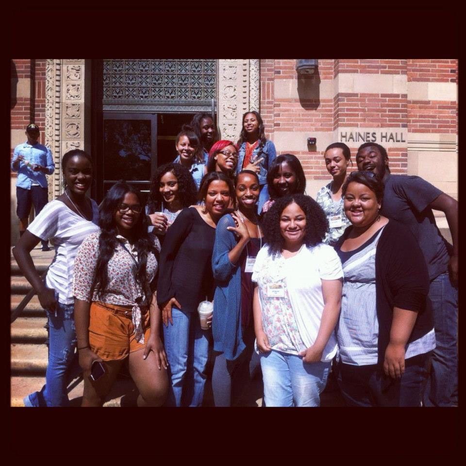 A group of students pose together on the steps outside Haines Hall at UCLA, with several participants wearing name badges and smiling at the camera.