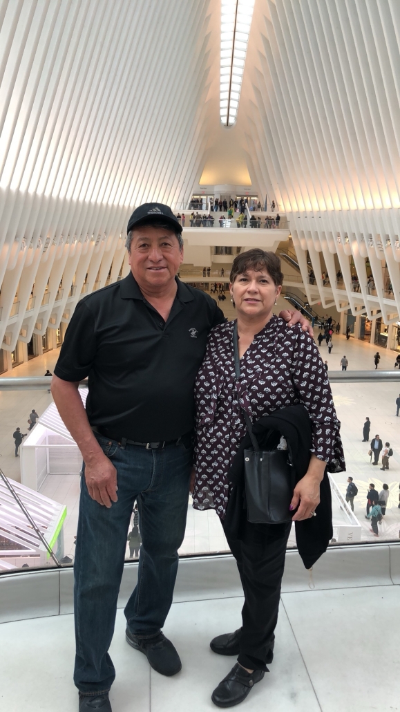 A man and woman pose together inside the Oculus transportation hub in New York City, surrounded by its white architectural ribs.