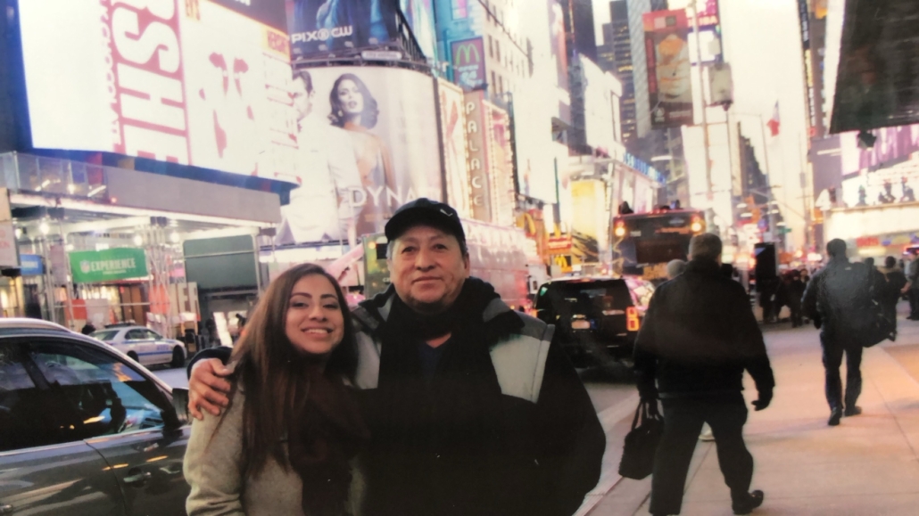Aranzazu smiles beside a man with his arm around her while visiting Times Square in New York City.